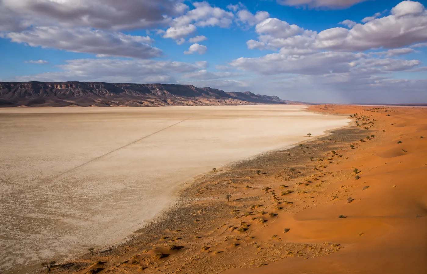 The flat white clay bed of Lac Iriki shimmering under a desert sky